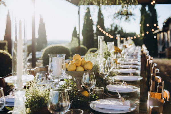 in the back yard of the old villa there is a long festive table, which is decorated with lemons and herbs, on the table are plates, glasses and candles. Wedding in Italy. Tuscany